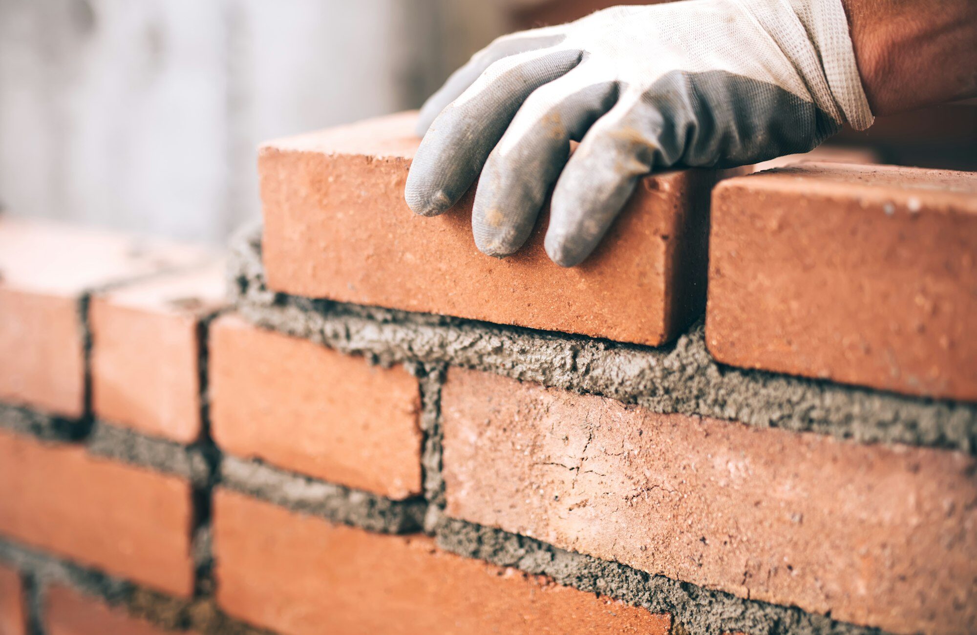 Close up of industrial bricklayer installing bricks on construction site